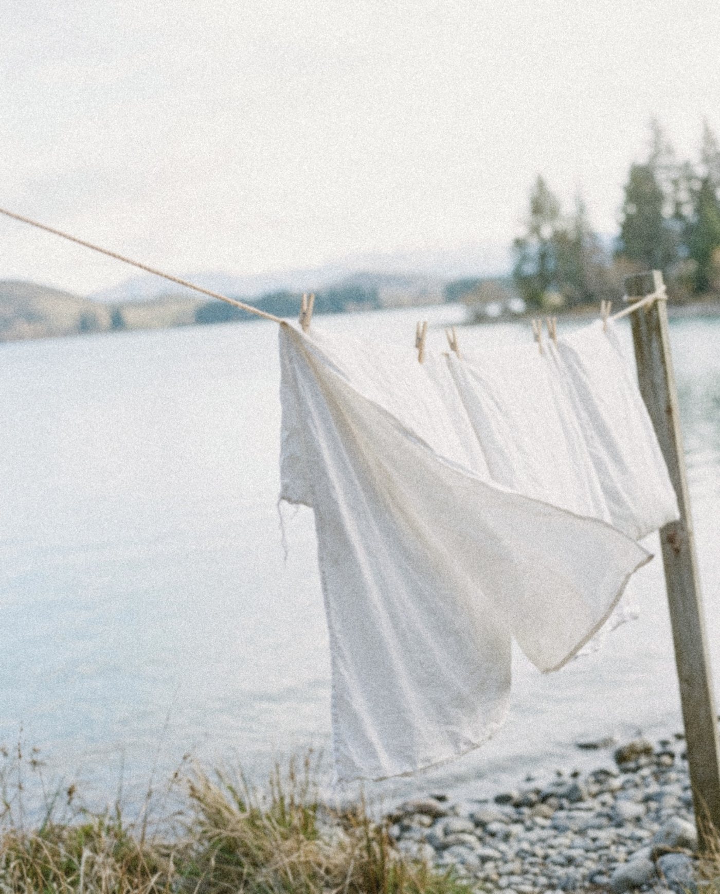 White sheets drying on a clothesline beside a calm lake