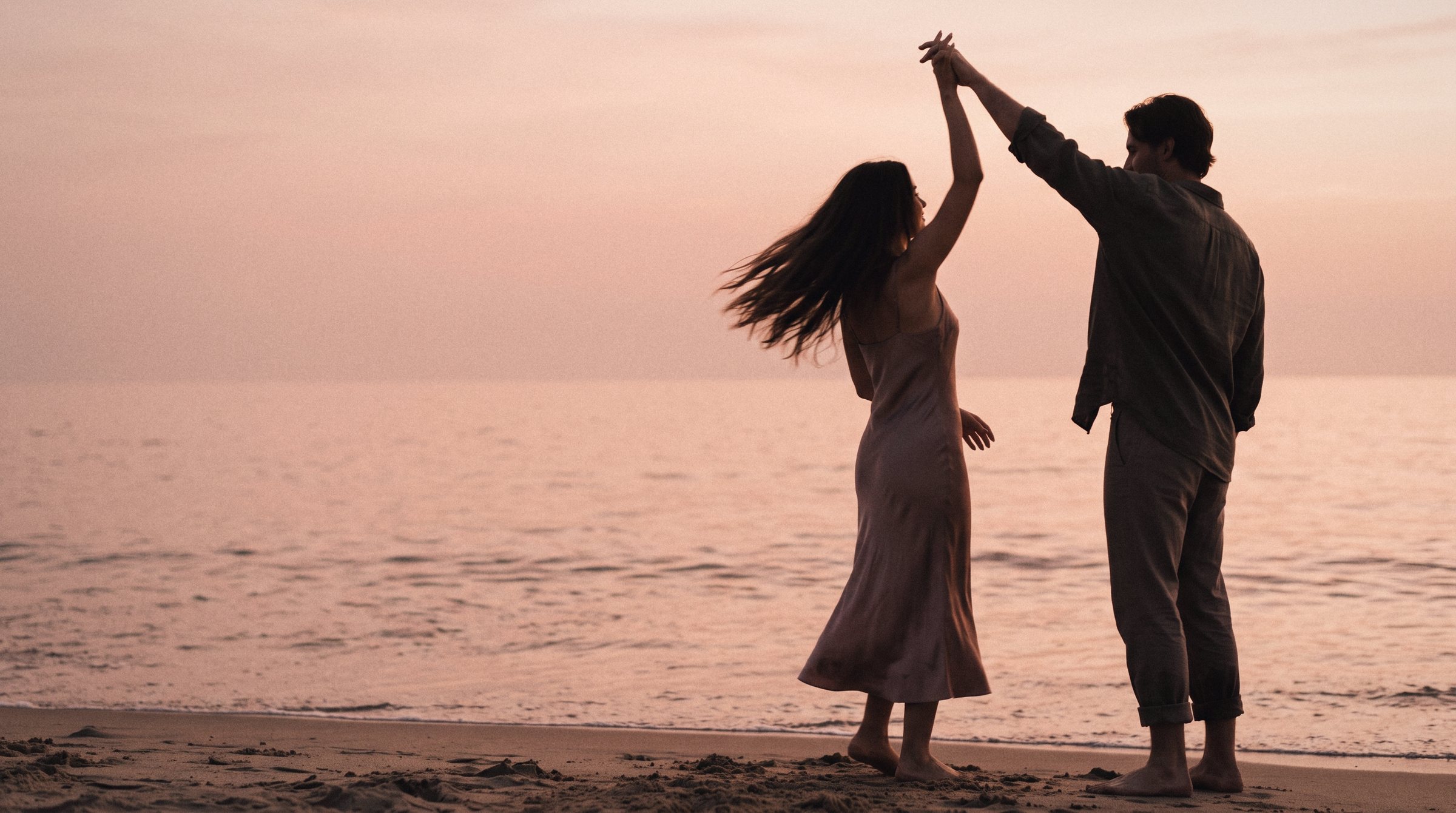 A couple dancing on the beach at sunset