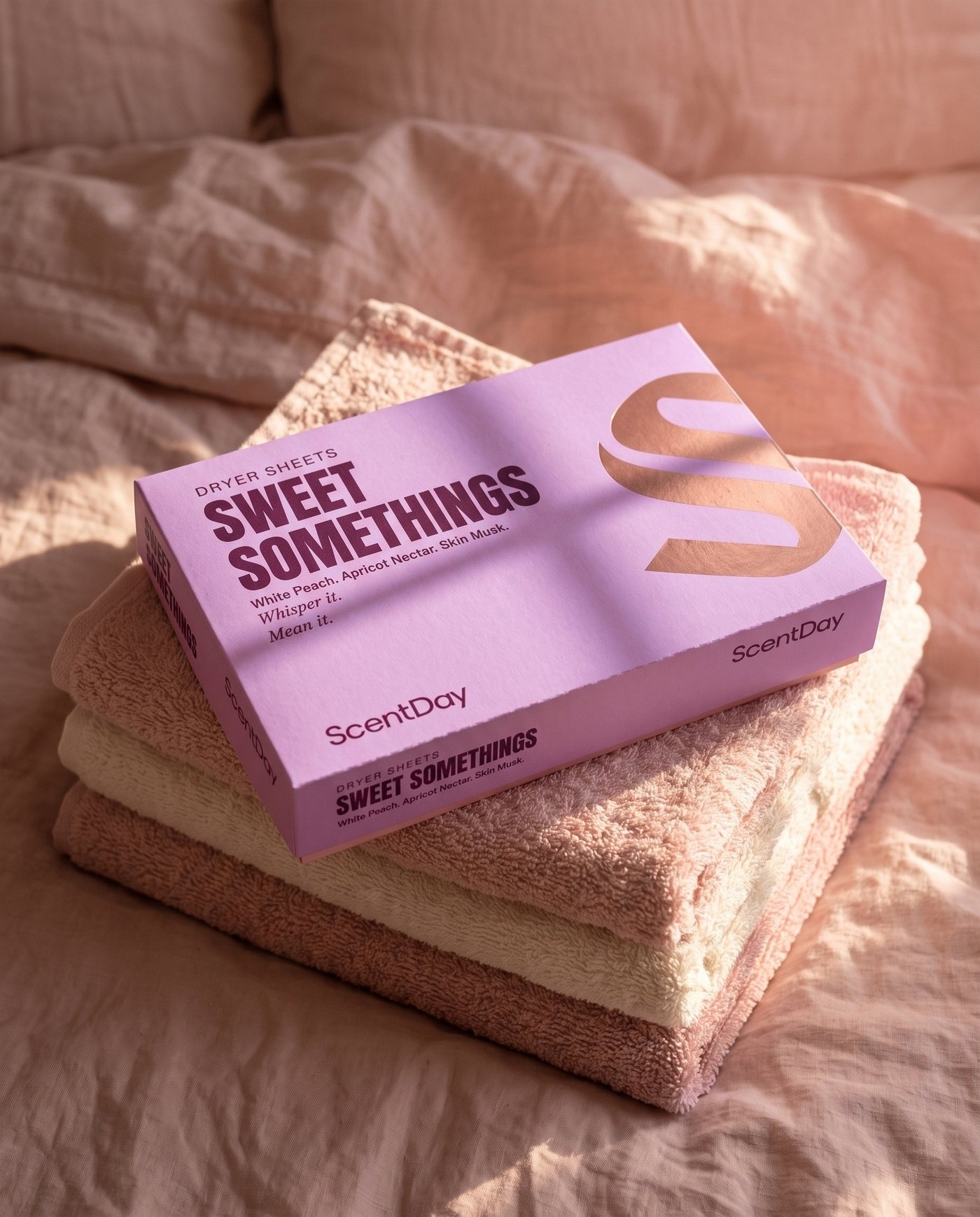 Sweet Somethings dryer sheets box on a stack of blush and cream towels