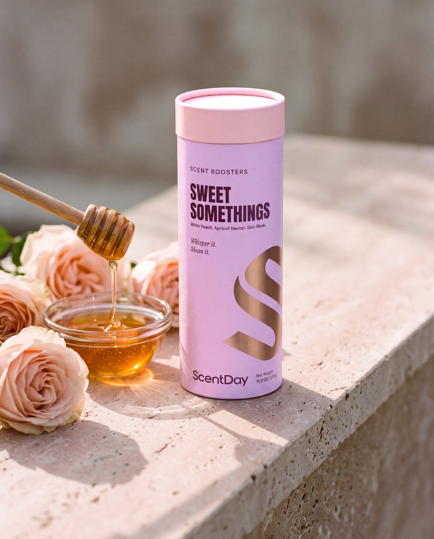 Sweet Somethings scent booster tube on a travertine ledge beside pink roses
