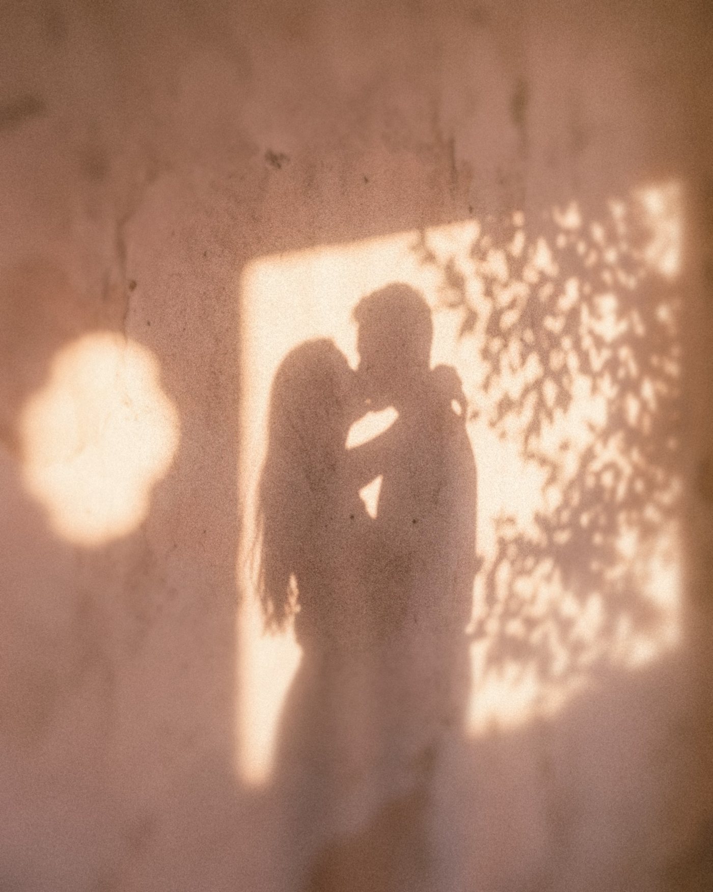 The shadow of a couple kissing on a sunlit plaster wall