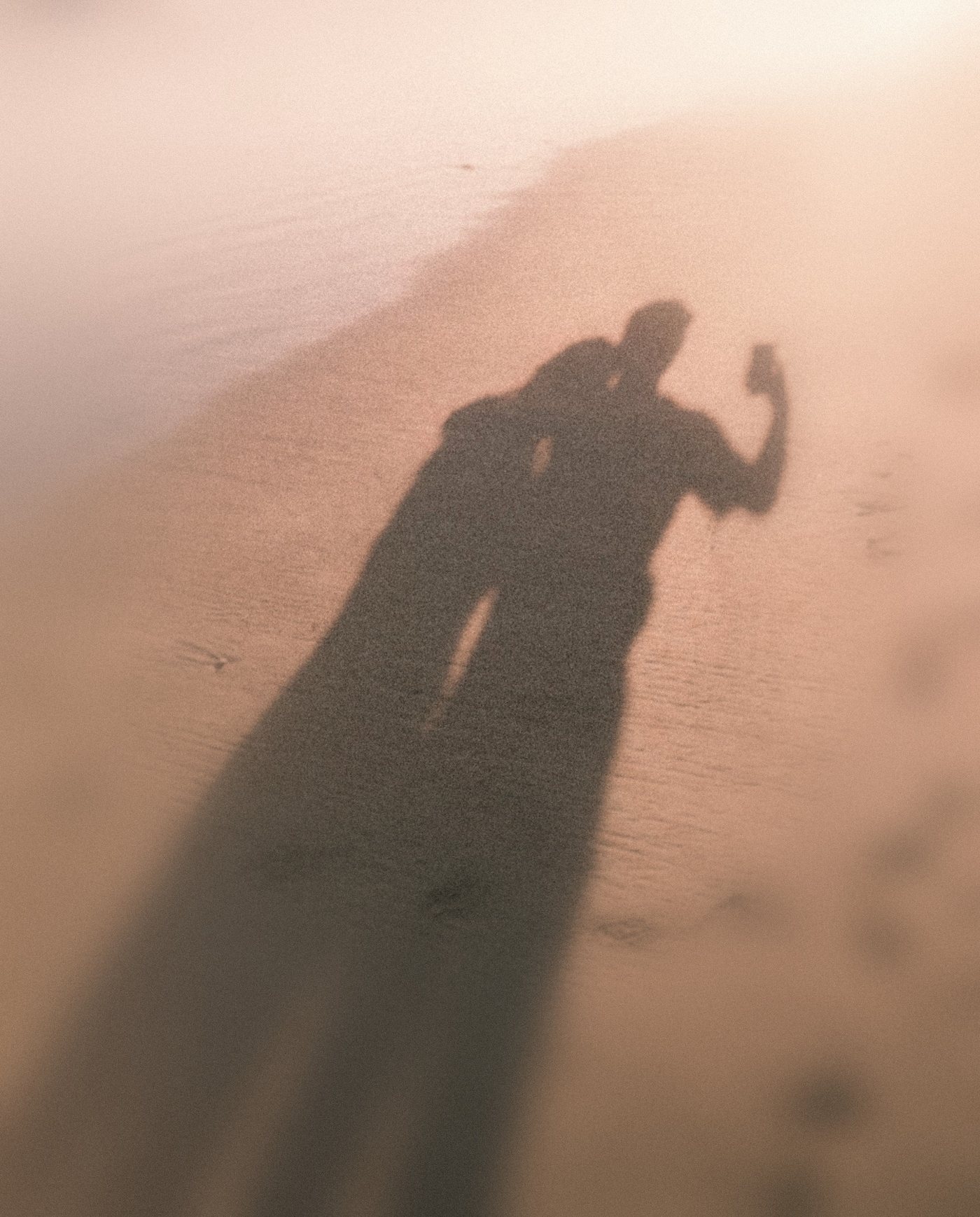 The shadows of a couple taking a selfie on the sand